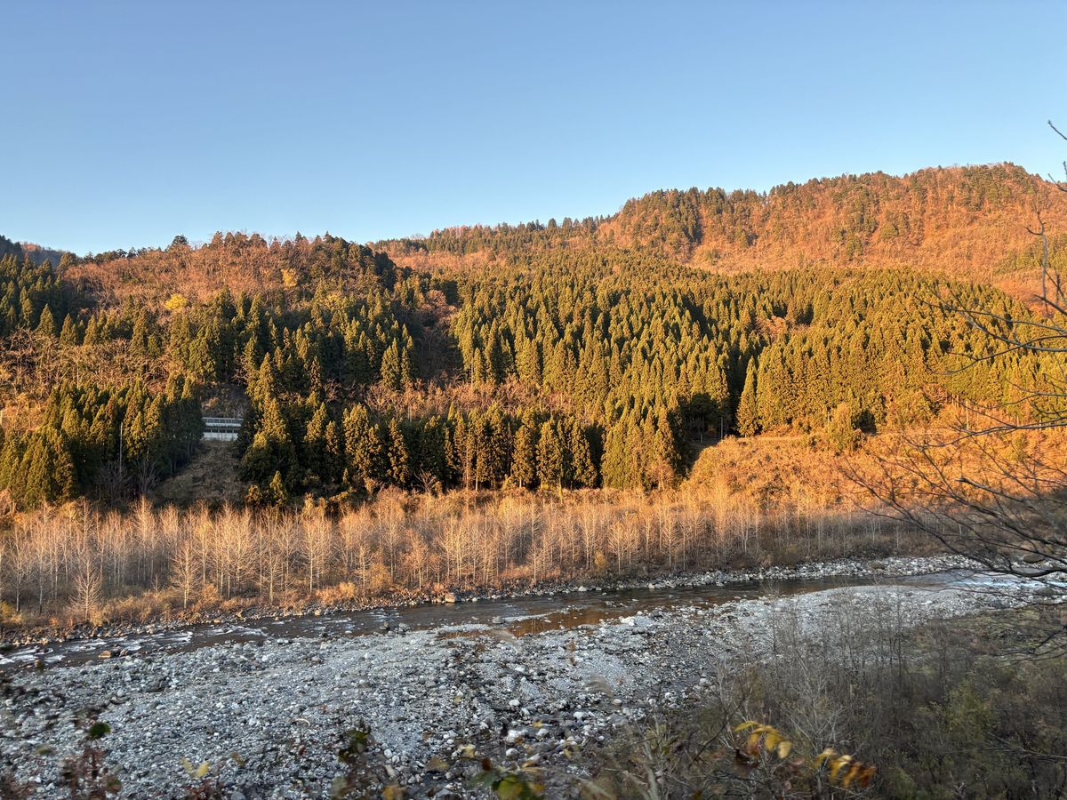 View of the Joganji River and sunset mountains from a Toyama Chiho Railway Tateyama Line train window