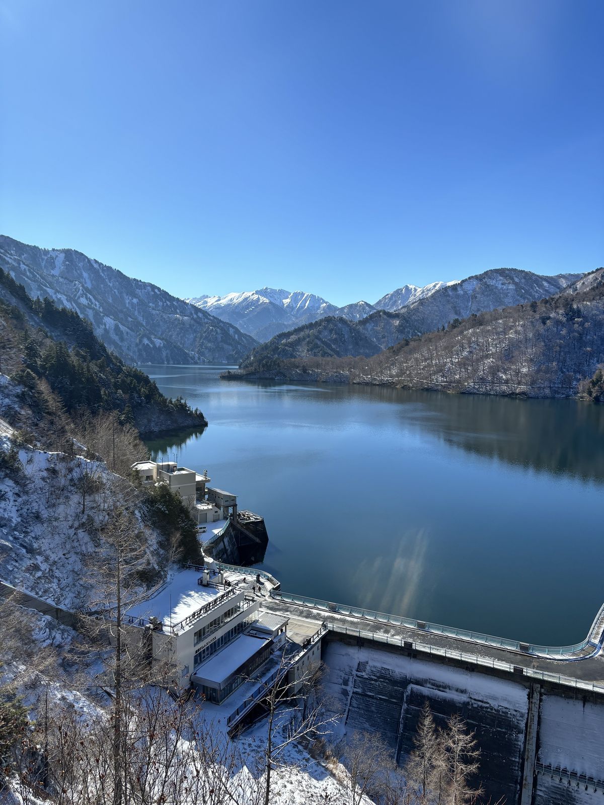 Kurobe Dam facilities and the deep blue reservoir spread out among snow-covered mountains in winter