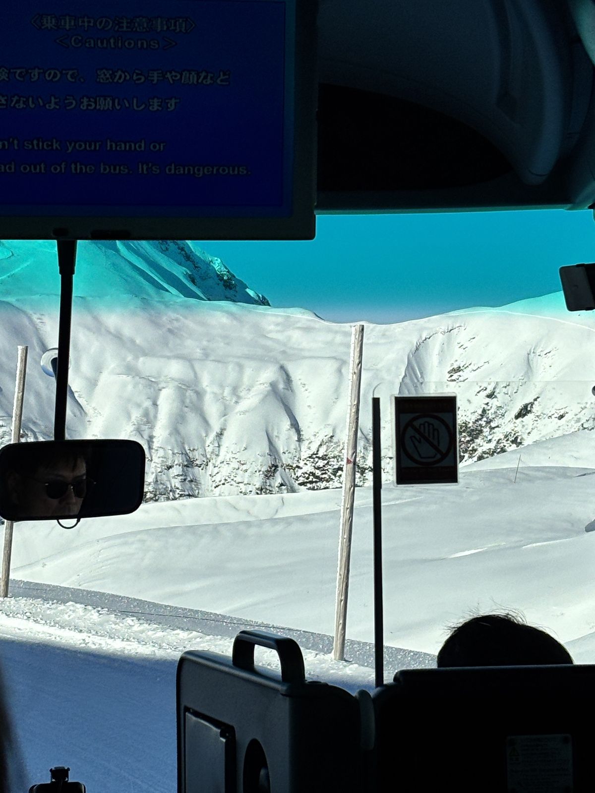 Snow-covered mountain slopes seen through a bus window on the ride up to Murodo, Tateyama