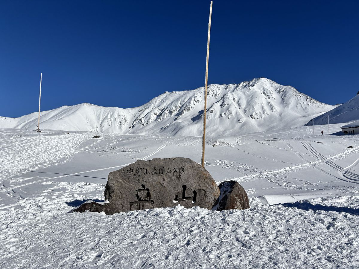 Stone monument inscribed with Tateyama standing on a snowy slope at Murodo under a crystal-clear sky