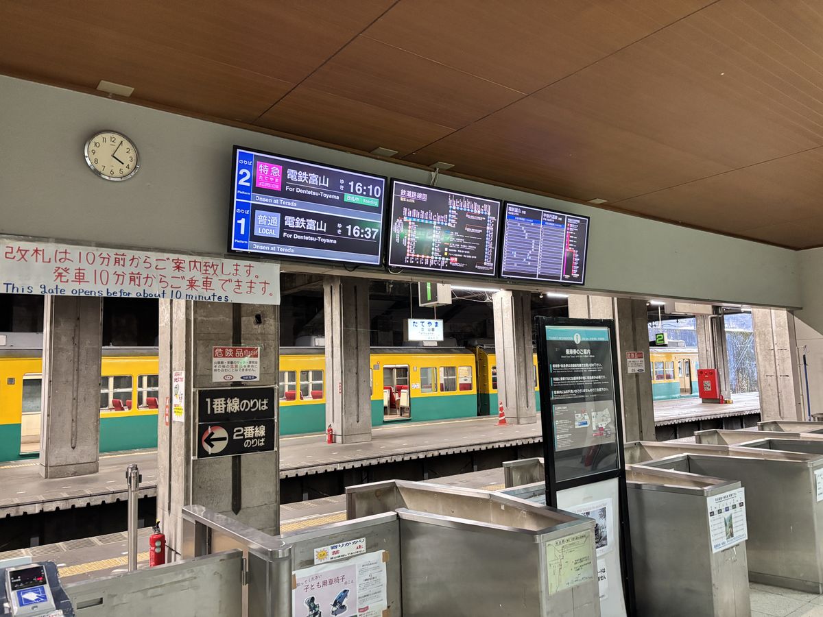 Departure board on the platform at Tateyama Station showing red 'Express' and 'LOCAL' train types with English text (Toyama Chiho Railway)