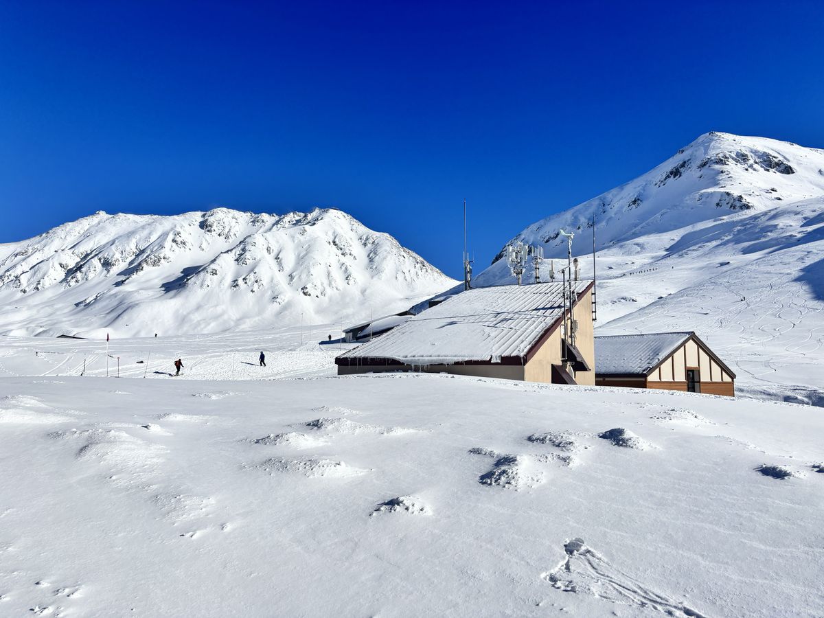 深雪中露出屋顶的山间小屋,头顶是室堂一带的湛蓝天空