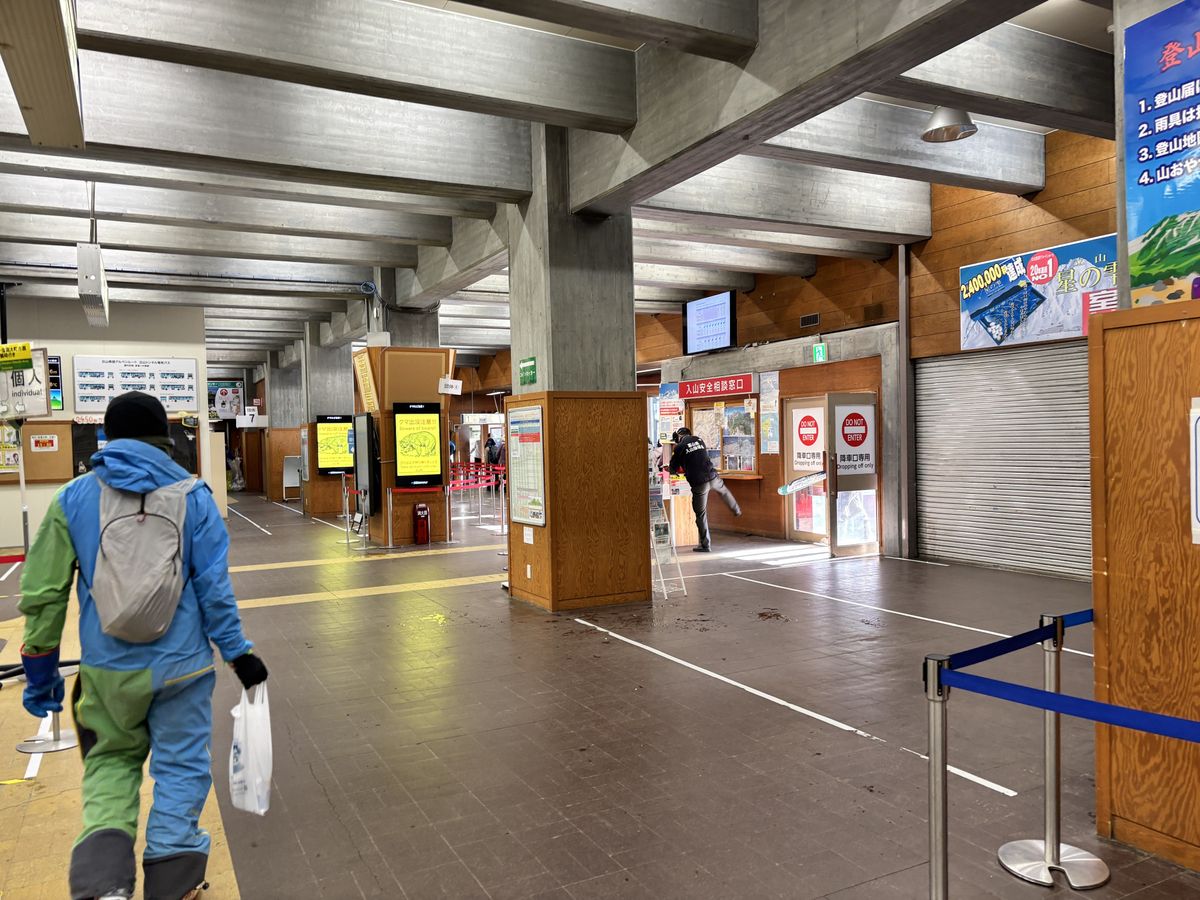 Hiker in winter gear walking past the information counter inside the Murodo Station bus terminal