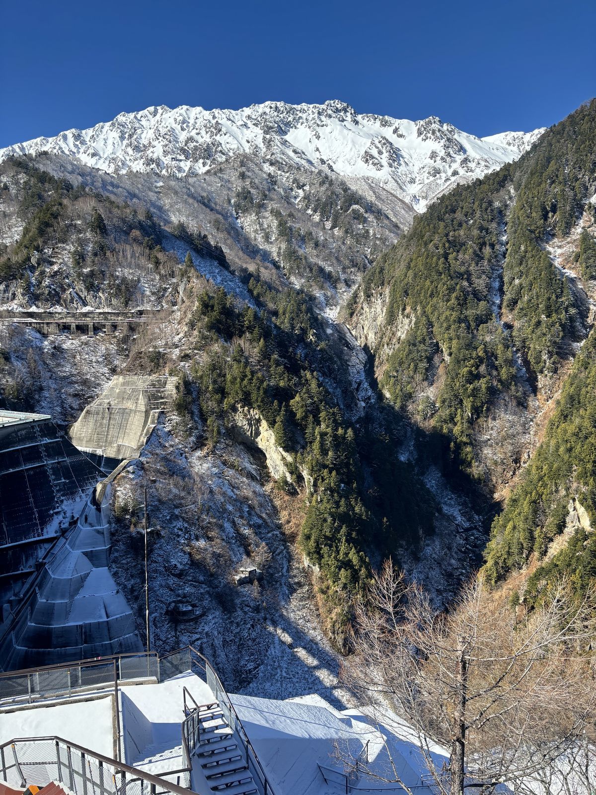 Dam structures standing in the valley above Lake Kurobe, ringed by snow-covered winter mountains