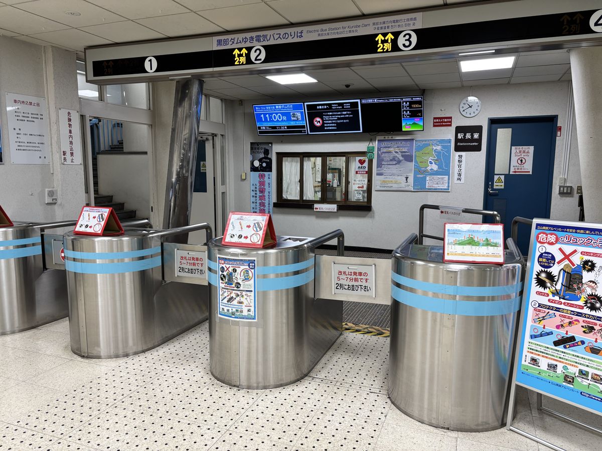 Ticket gates at the electric bus boarding entrance, lined with guidance signs and notices for passengers
