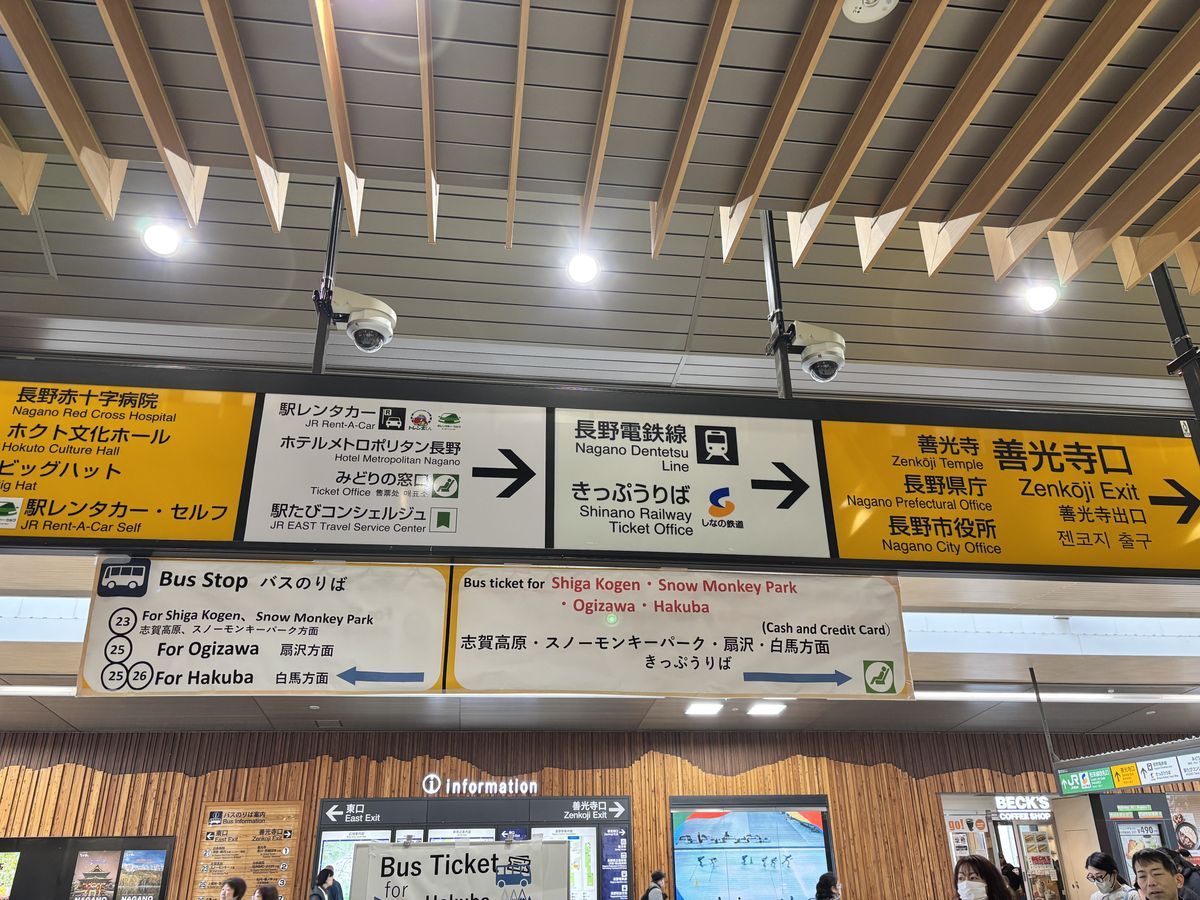 Overhead signs pointing to bus stops and ticket counters at the transfer station for the Tateyama Kurobe Alpine Route