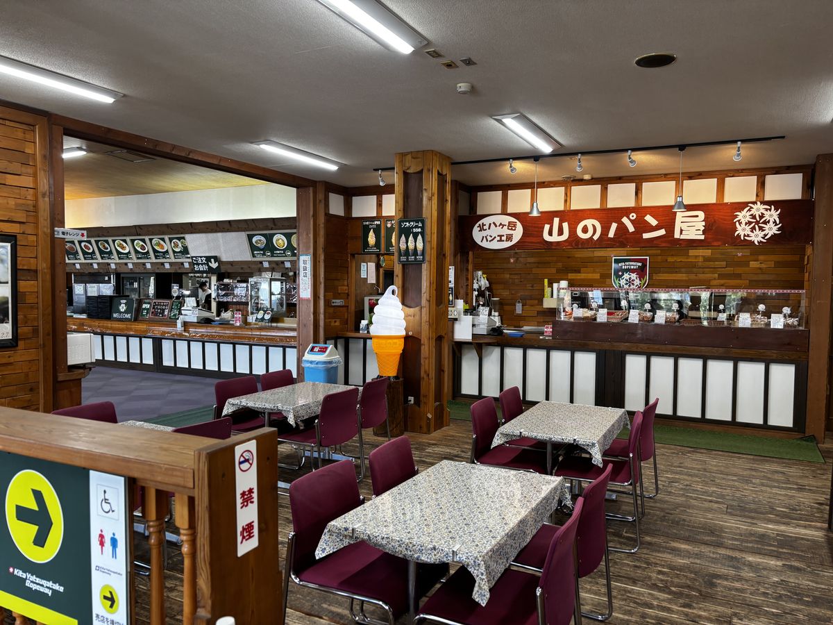 Mountain bakery kiosk with a soft-serve model and red chairs in the wooden rest area at the summit station