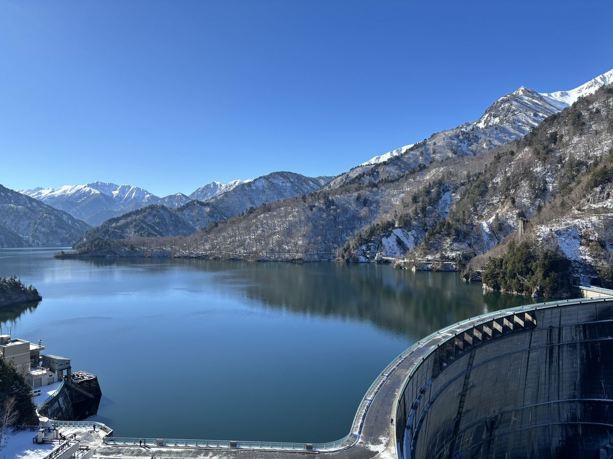 黒部ダム 雪山に囲まれた静かなダム湖と、緩やかに弧を描く堤体