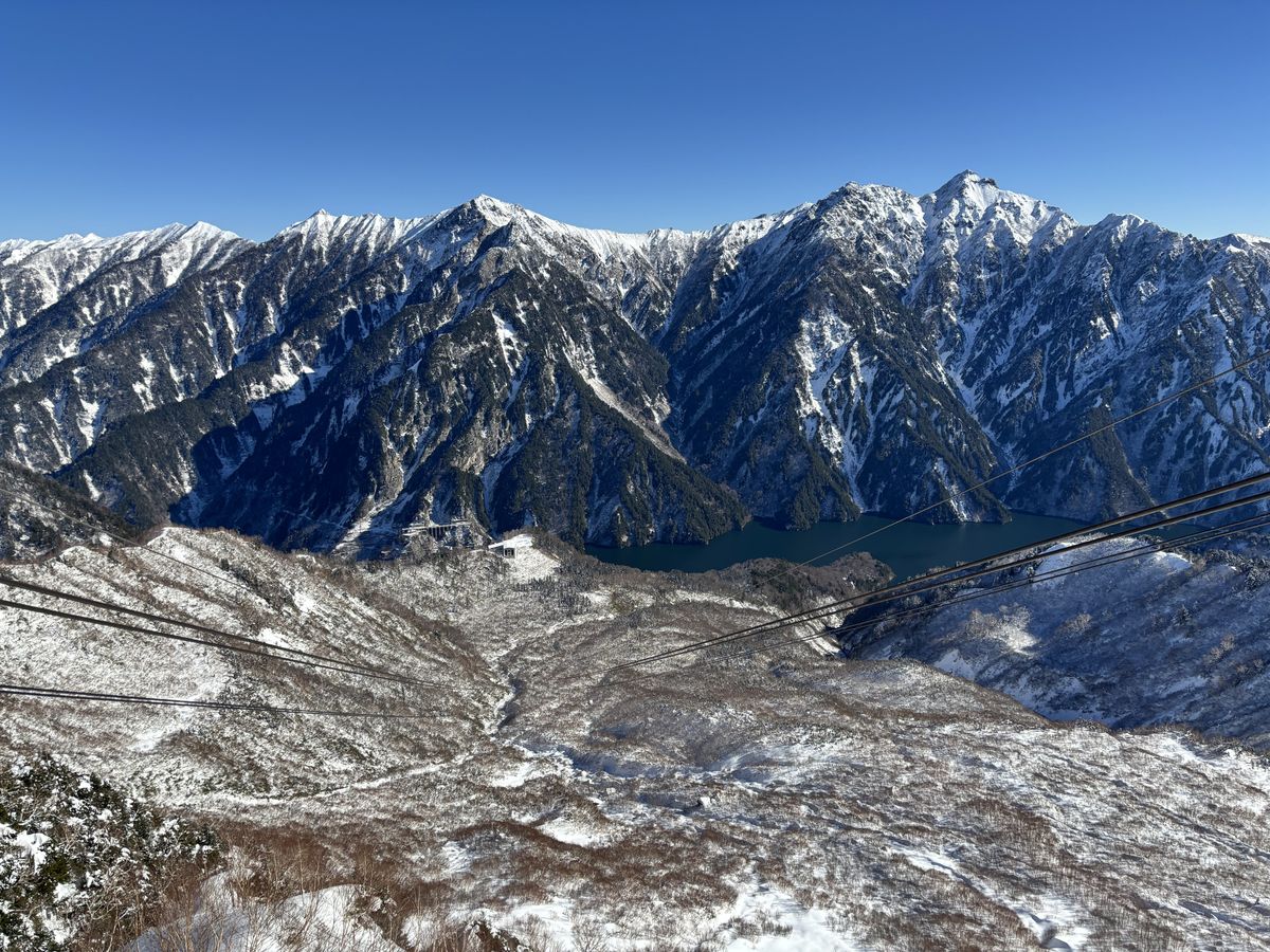 Winter view from the Tateyama Ropeway, looking past the cables to jagged snowy peaks and a blue-green lake