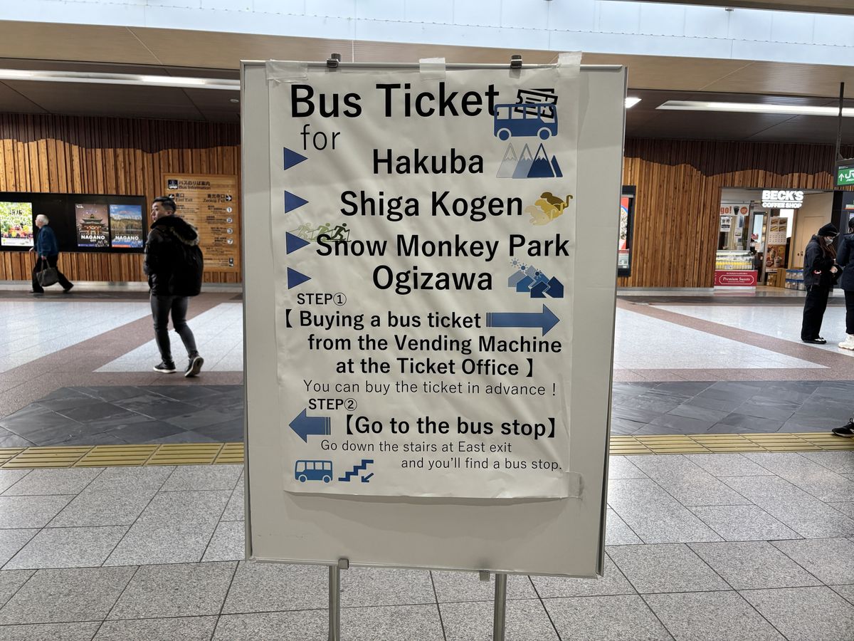 Large overhead sign in the Nagano Station concourse explaining how to buy tickets for the bus
